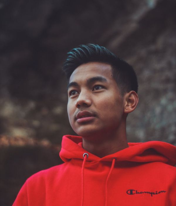 Man in a calm focused pose against a warm dust colored background.